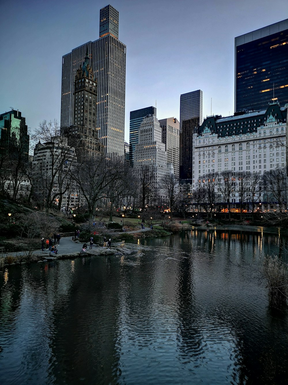 a lake in a city with tall buildings in the background