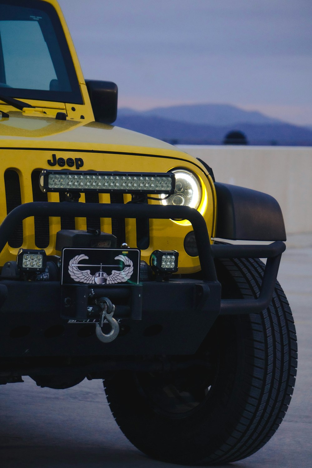 a yellow jeep is parked in a parking lot