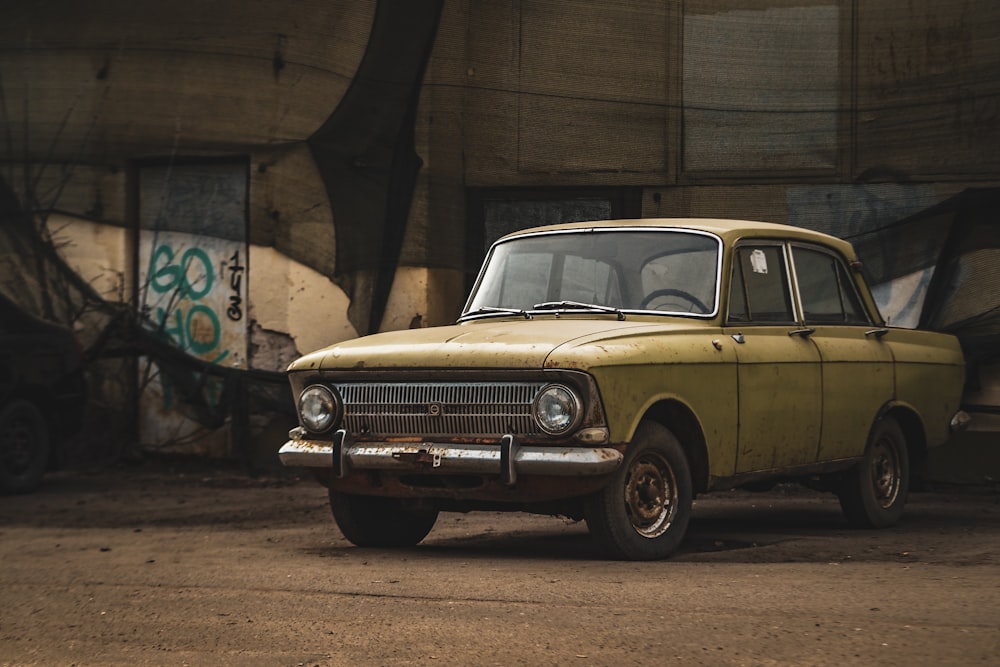 an old yellow car is parked in a parking lot