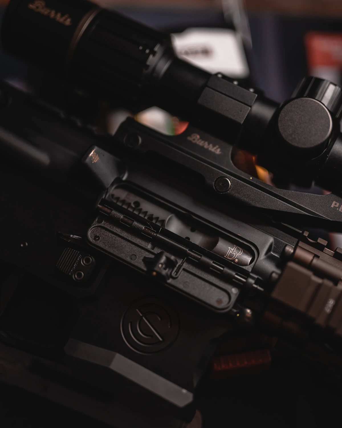 Macro de un visor montado sobre el receptor de un rifle, luz cálida.