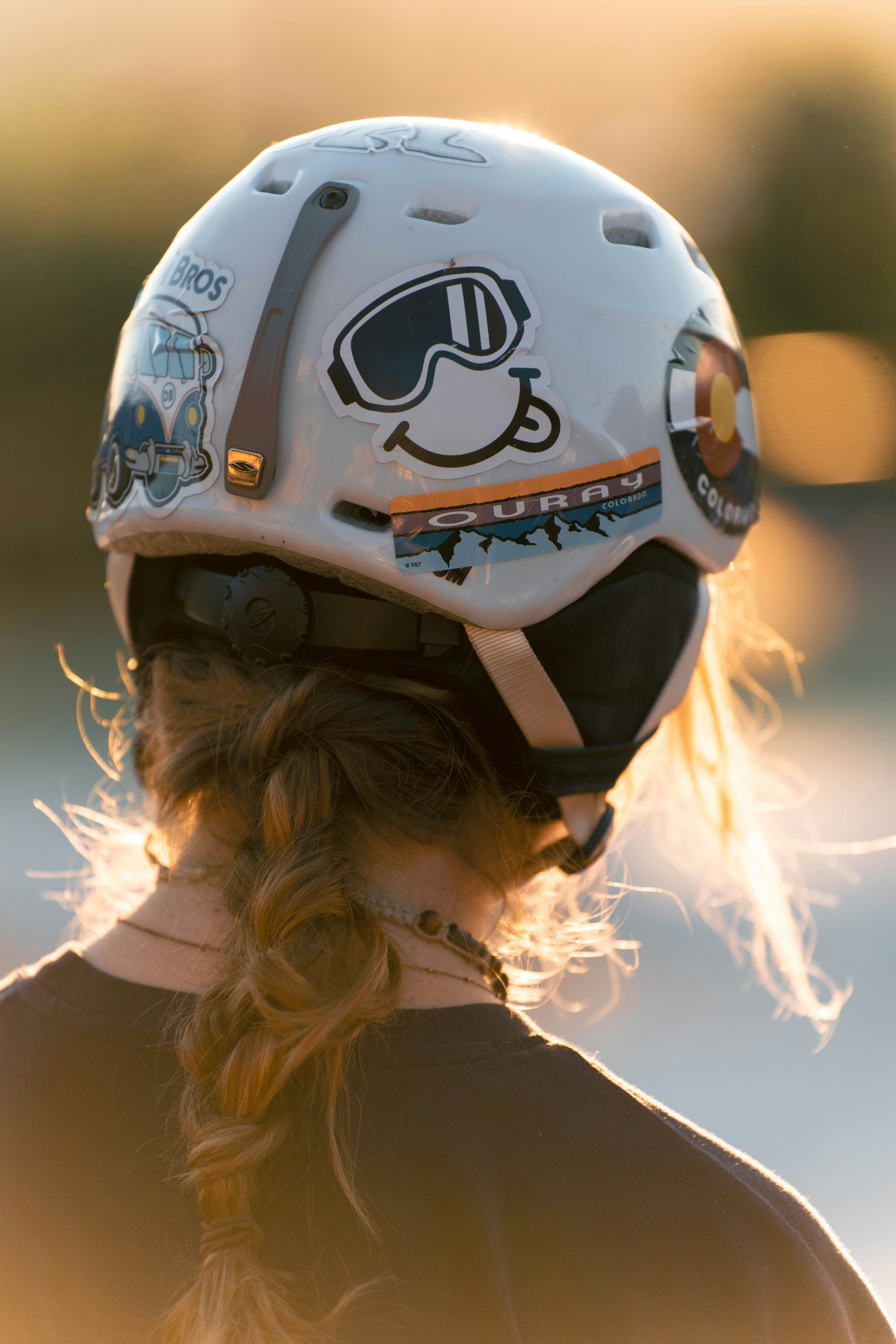 A young rider adjusting her brown leather helmet under soft natural light.