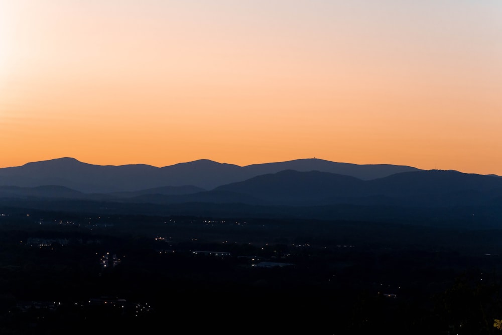 the sun is setting over the mountains in the distance