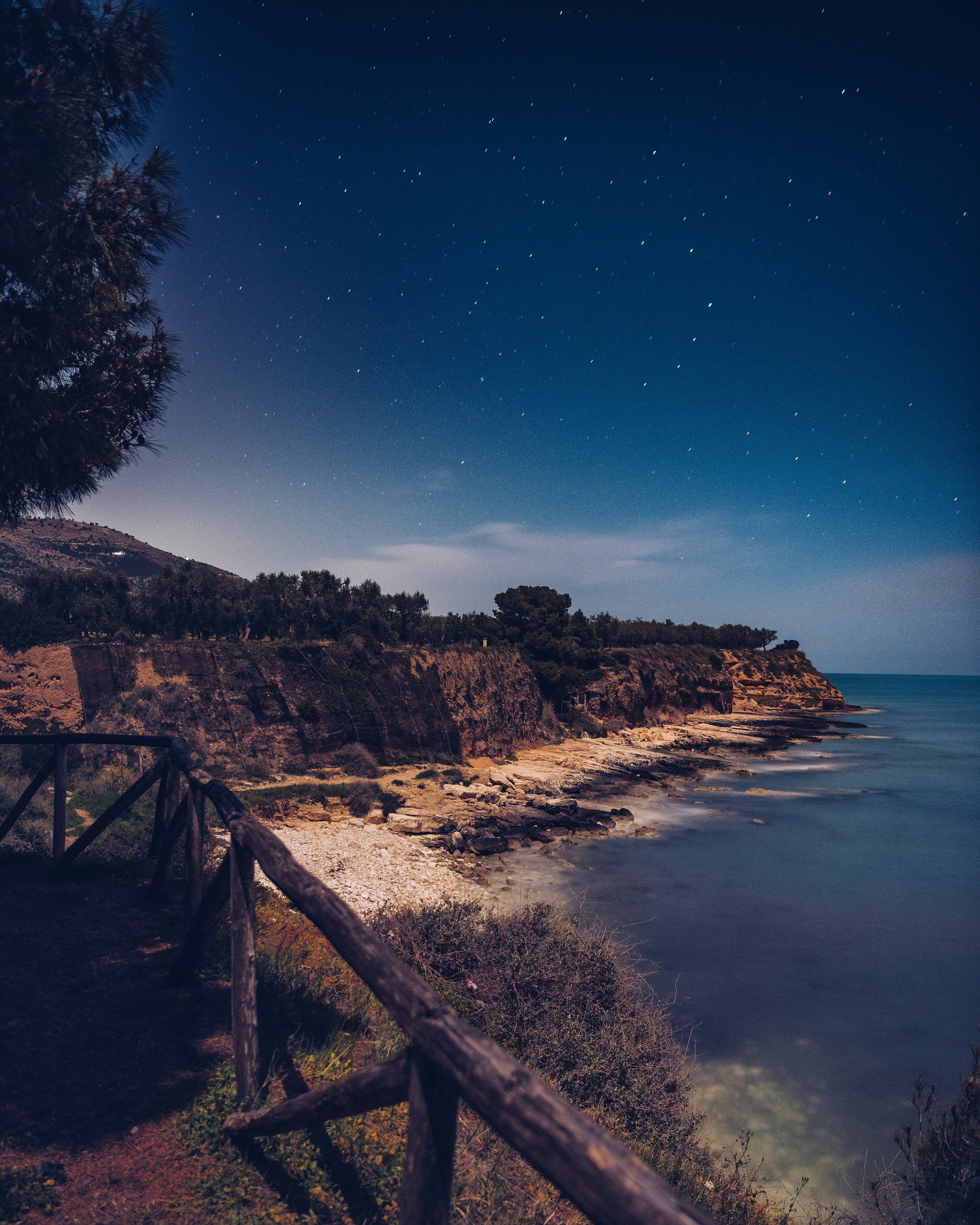 une vue nocturne d’une plage avec une clôture en bois