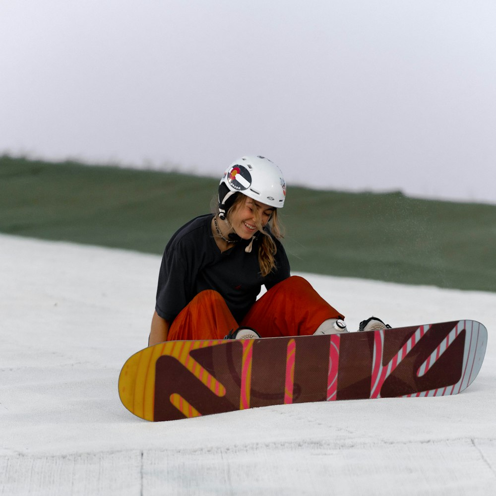 a woman sitting on the ground with a snowboard