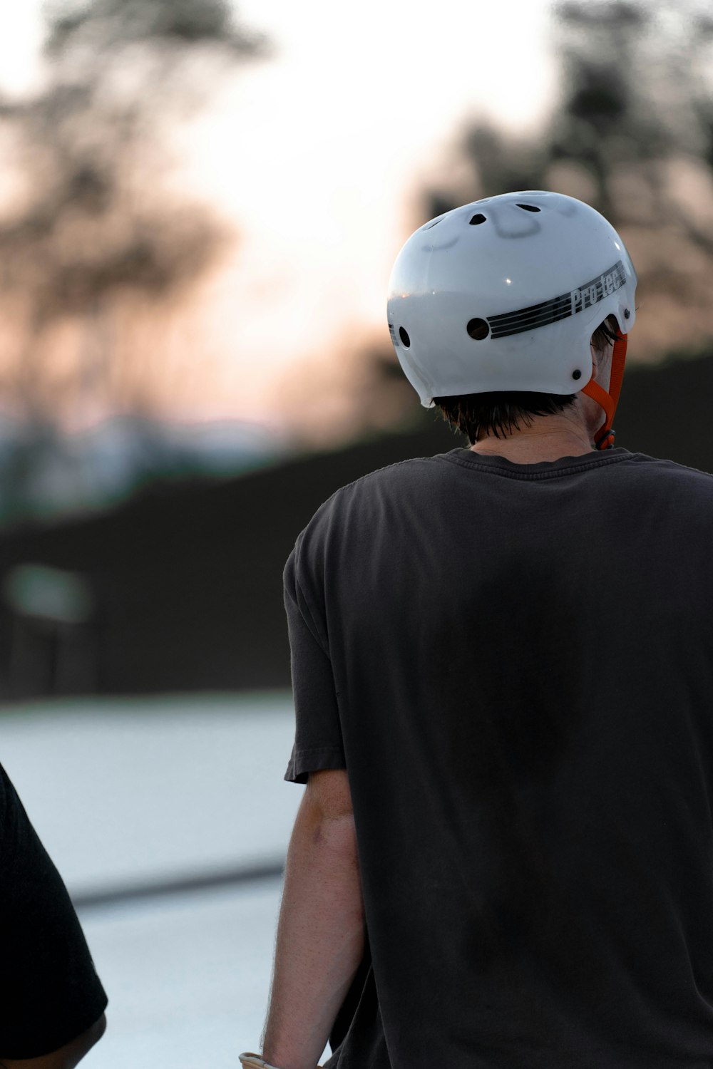 a man wearing a white helmet standing next to another man