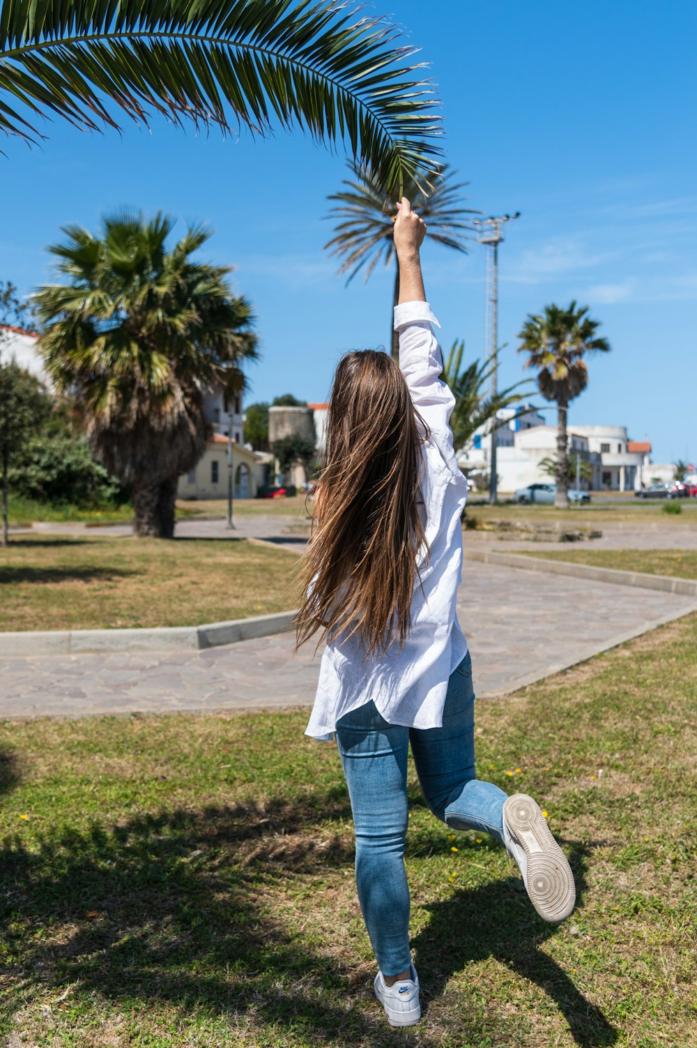 a woman in a white shirt is holding a palm tree