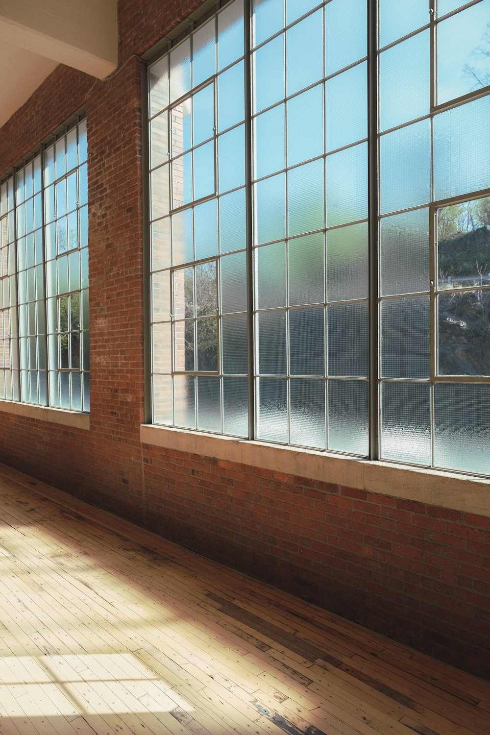 an empty room with large windows and wooden floors