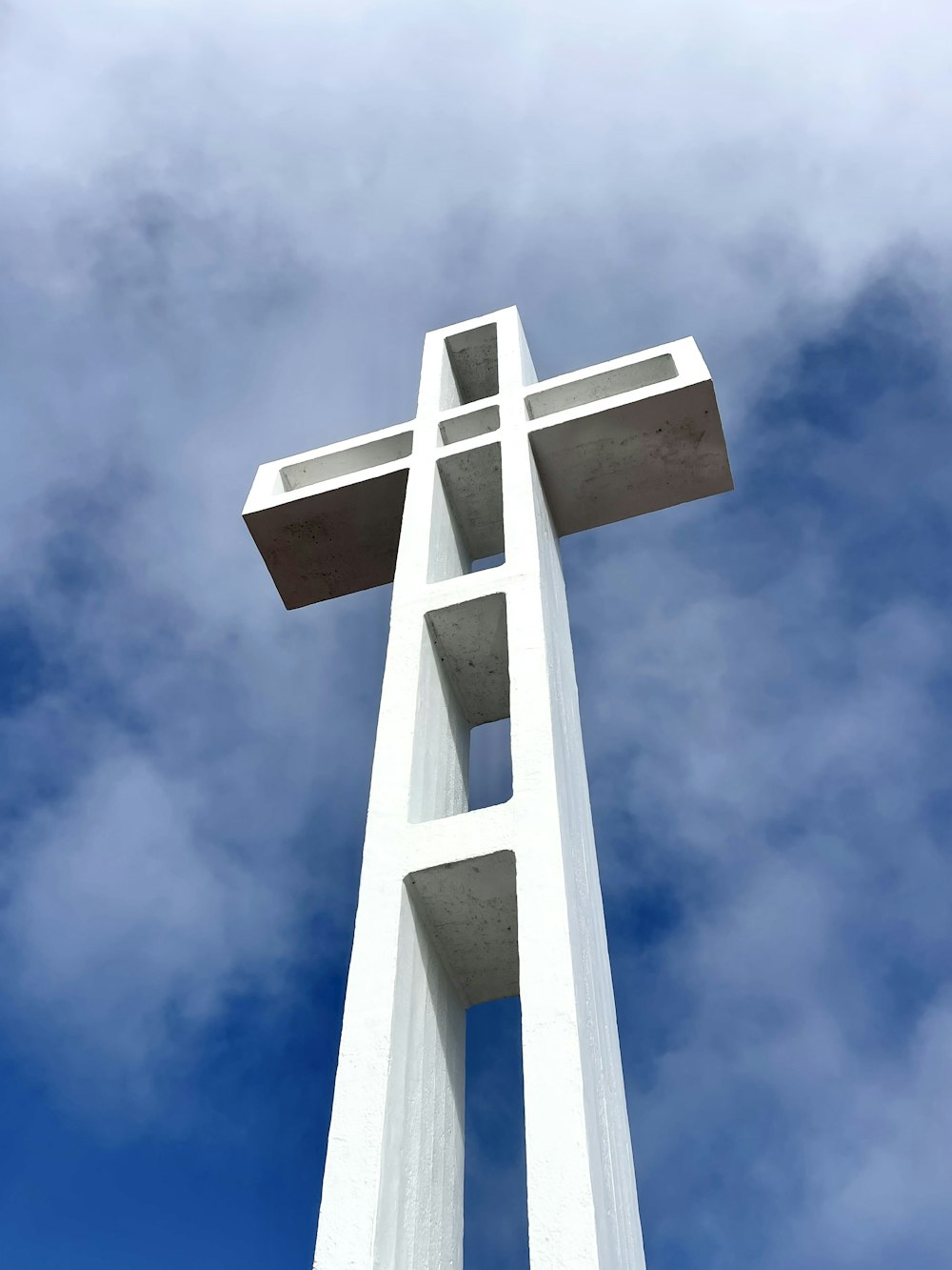 a tall white cross with a sky background