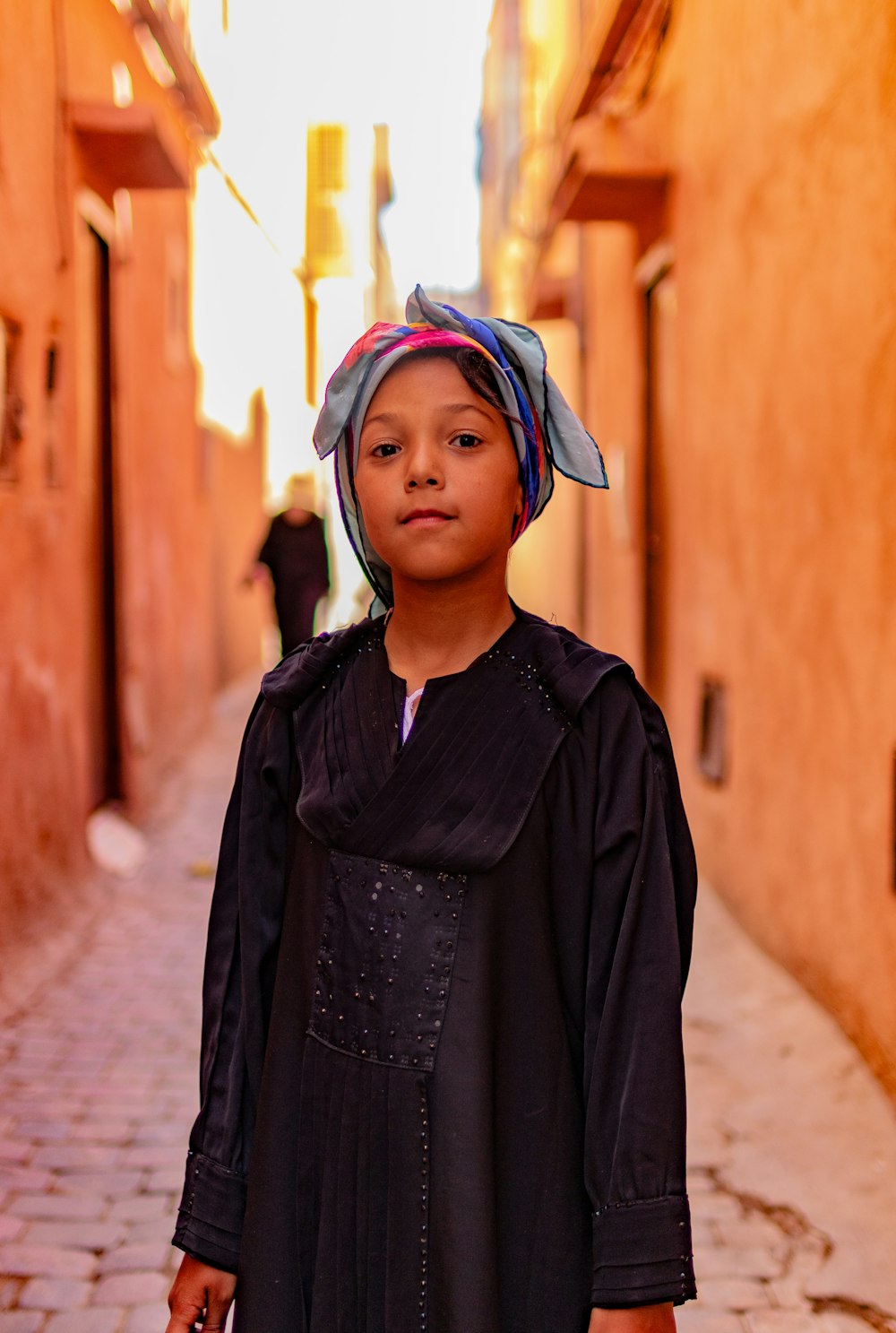 a young girl in a black dress and a turban on her head