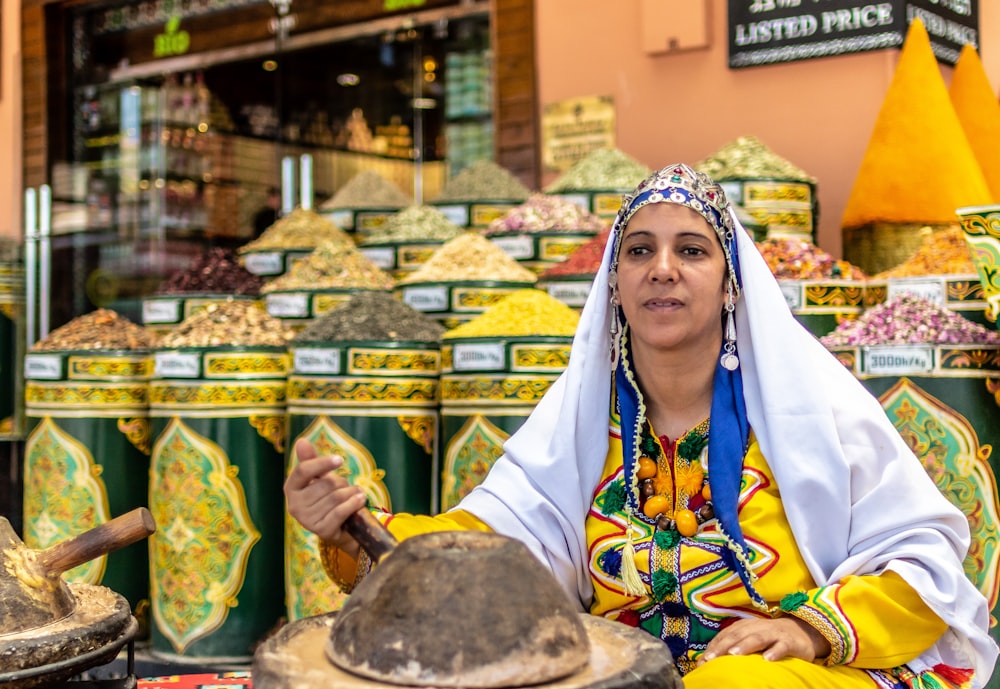 a woman sitting in front of a display of spices