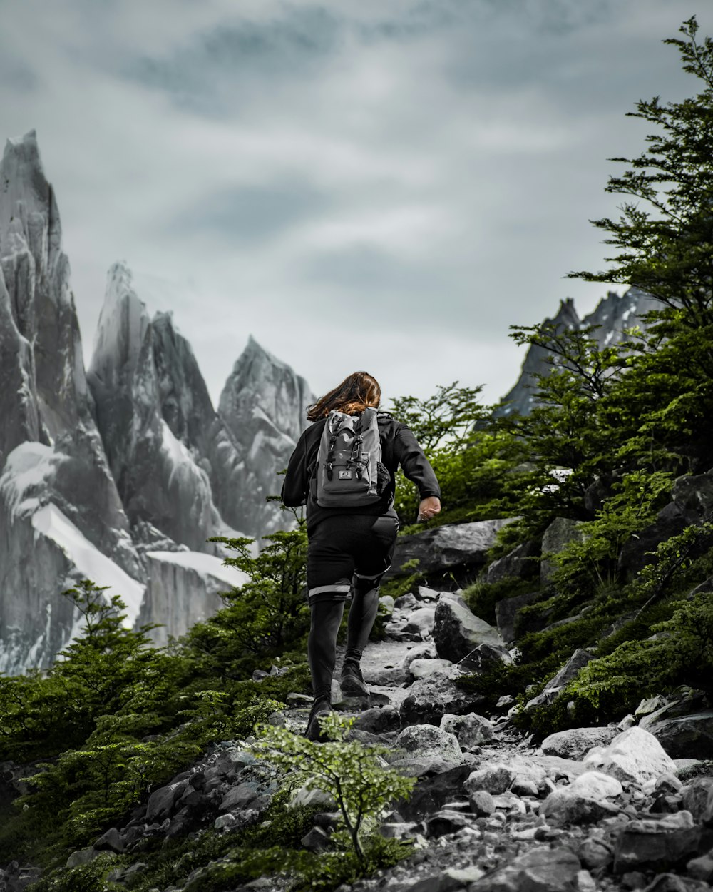 a woman hiking up a rocky trail in the mountains