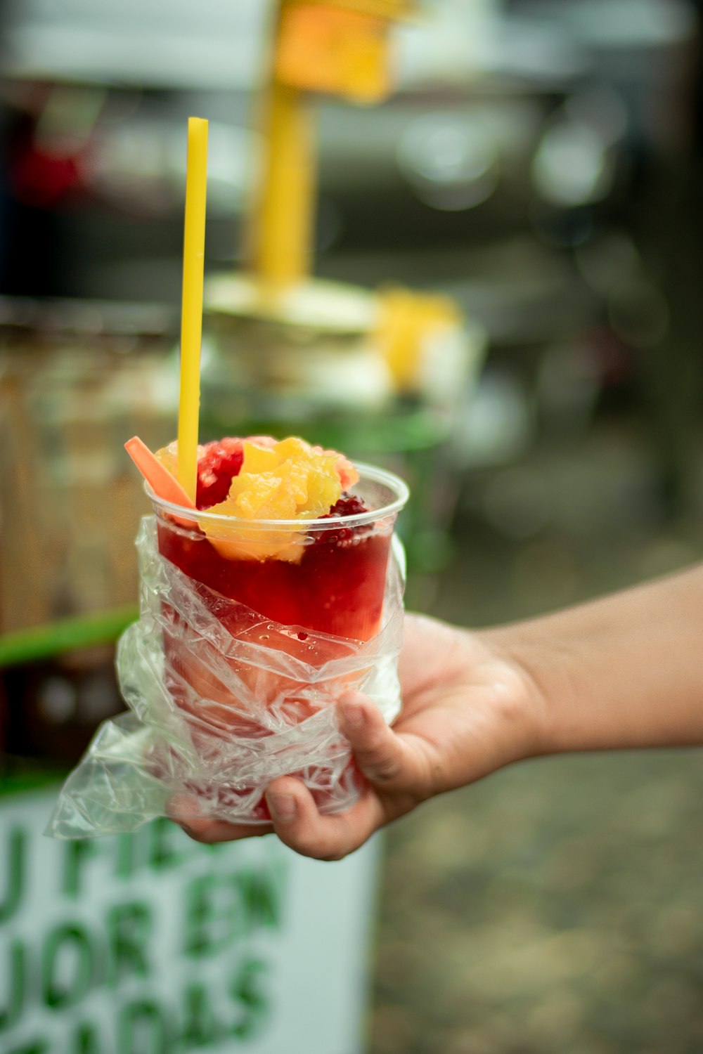a person holding a plastic cup filled with fruit