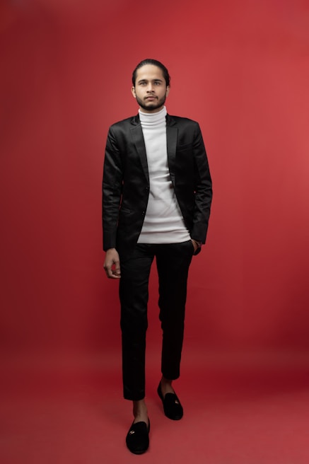 A cinematic shot of a founder in a sharp suit against a stark black background with signal orange accents.