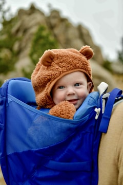 a little boy wearing a bear hat in a backpack