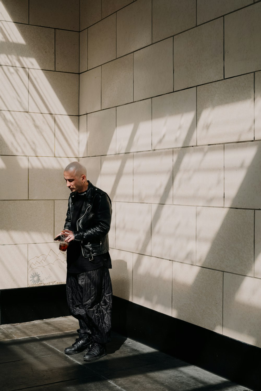 a man standing in front of a wall looking at his cell phone