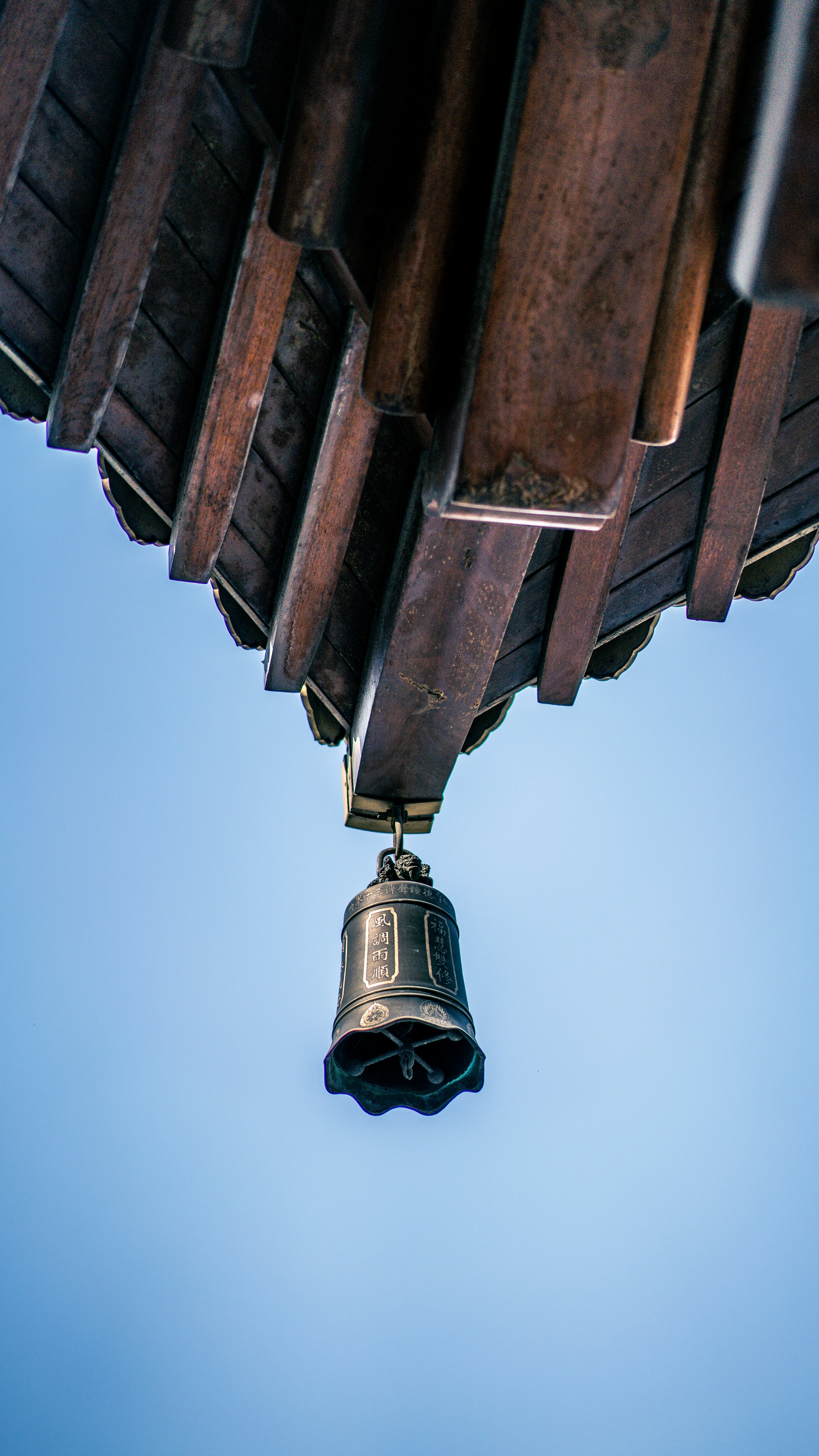 eine Glocke, die an der Seite einer Holzkonstruktion hängt