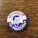 A vintage campaign button featuring a portrait with the text 'WALLACE FOR PRESIDENT.' The background includes red, white, and blue colors with a stylized eagle symbol.