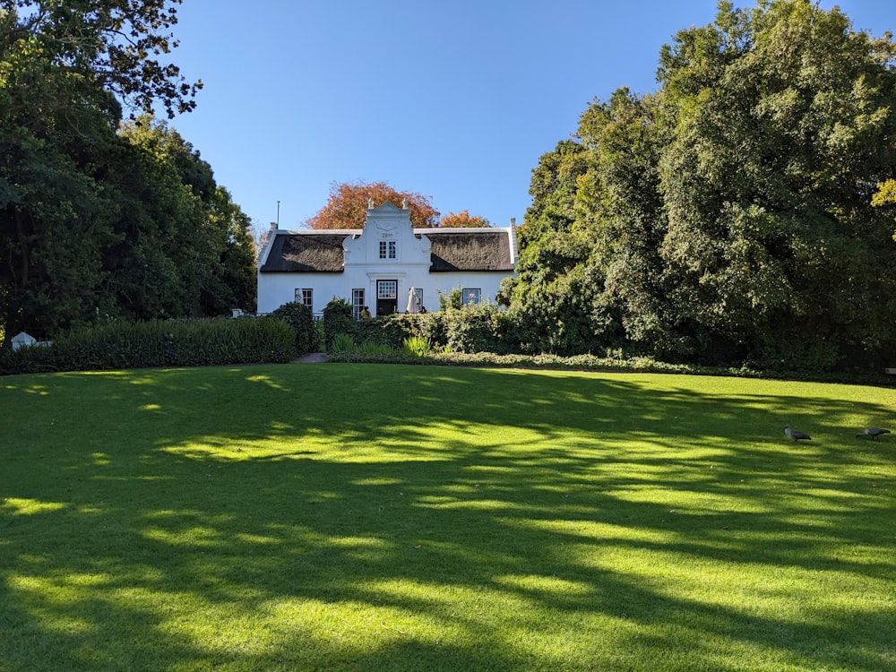 a white house surrounded by trees on a sunny day