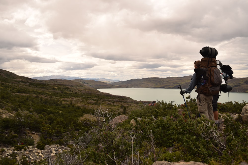 a man with a backpack and hiking poles walking up a hill