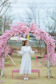 A grand floral arch with soft pink and white blooms framing an outdoor wedding altar.