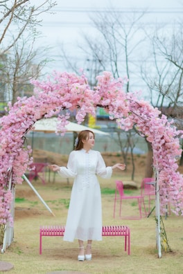 A grand floral arch with soft pink and white blooms framing an outdoor wedding altar.