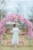 A stunning flower arch with soft pink and white blooms framing a wedding altar outdoors.