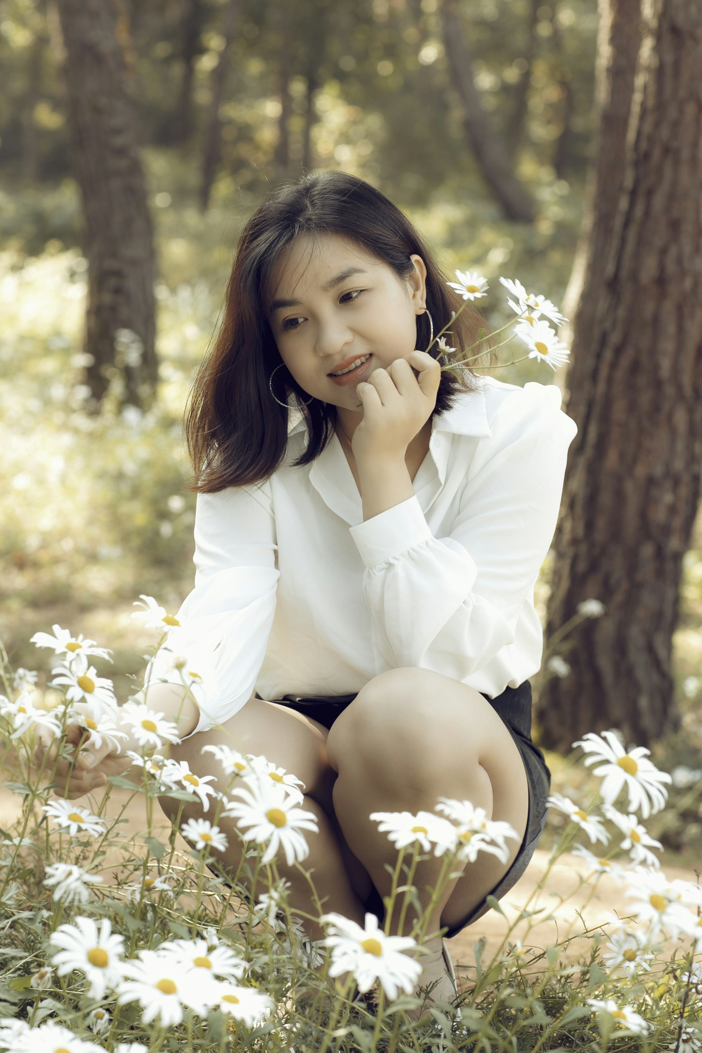 a woman sitting in a field of daisies