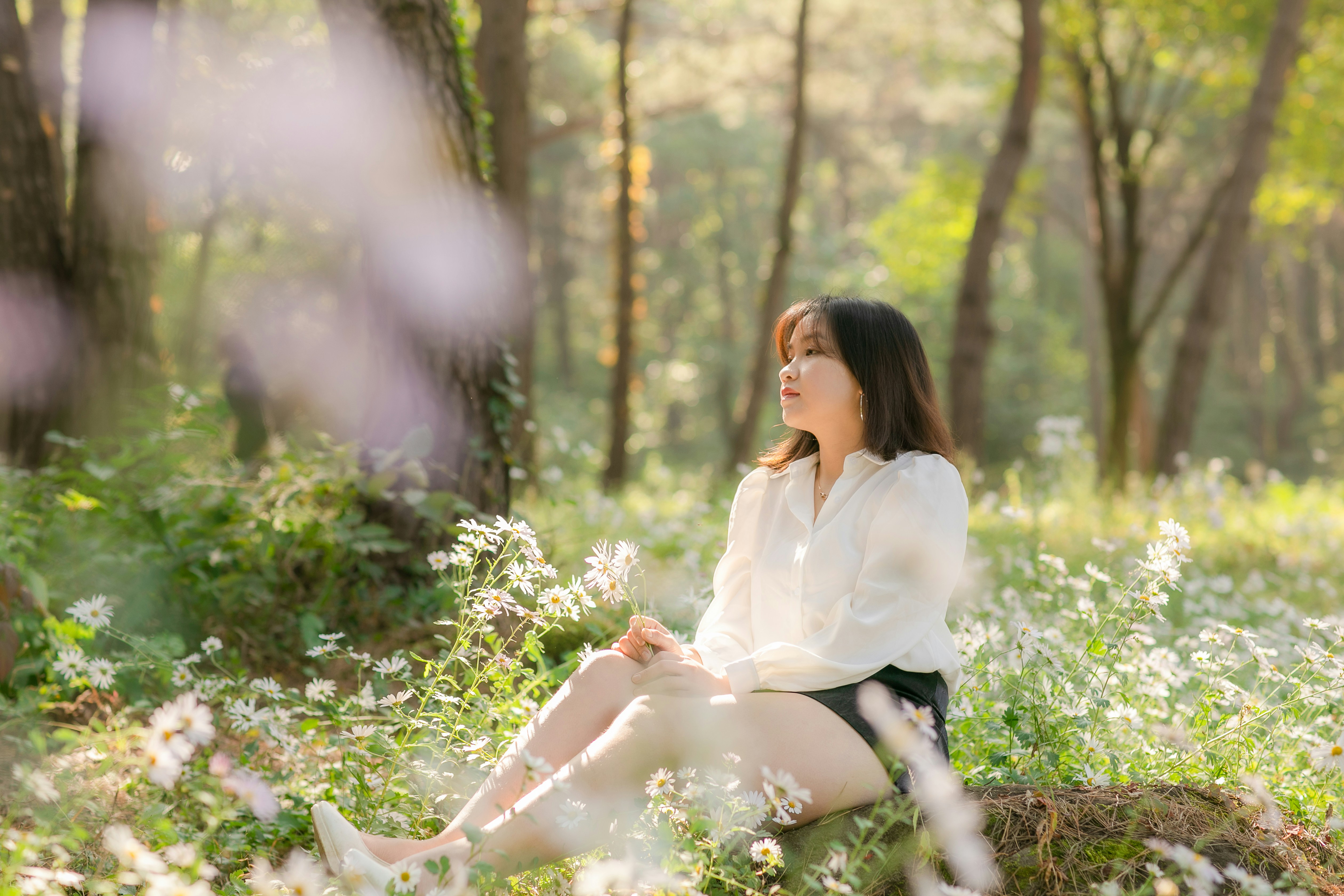 a woman sitting in the middle of a forest