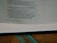 An open book displaying text with a focus on certain passages that discuss spiritual and moral themes. The page is light-colored with black printed text and a teal ribbon bookmark partially visible at the bottom. The book rests on a wooden surface.
