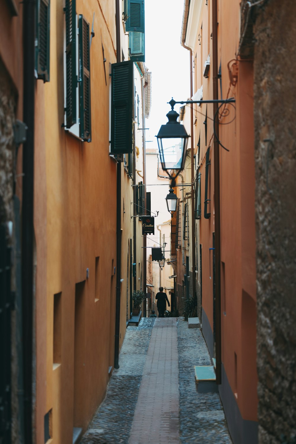 a narrow alley way with a lamp on the side