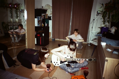 A group of students practicing guitar and piano together in a cozy music room.