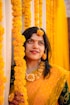 a woman in a yellow sari holding a garland