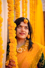 a woman in a yellow sari holding a garland