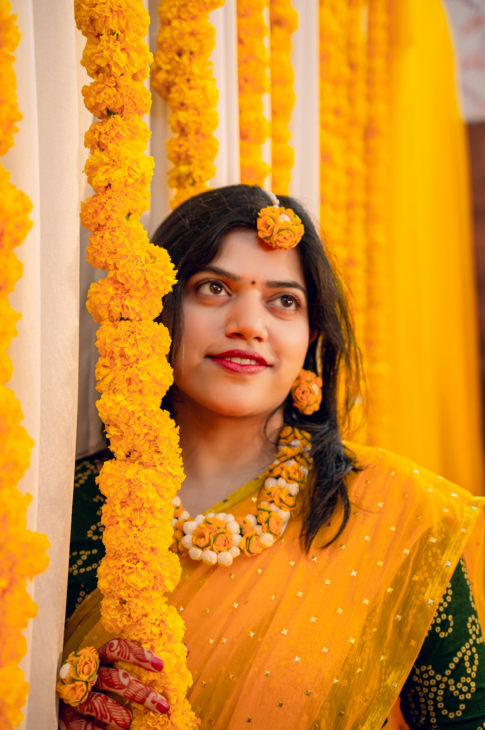 Una mujer en un sari amarillo sosteniendo una guirnalda
