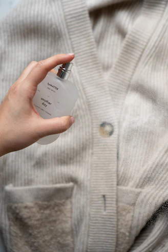 a person holding a bottle of perfume in their hand