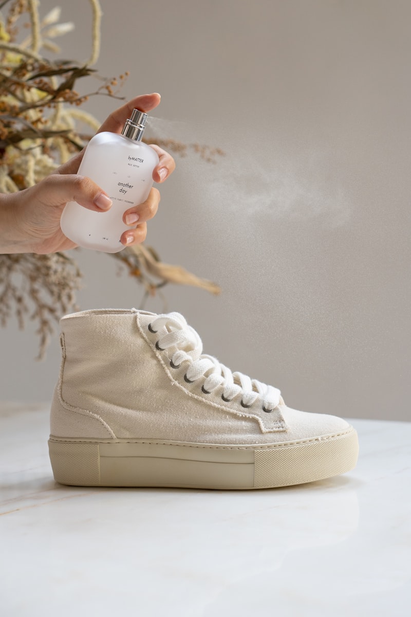 Reinigungsflasche und Sneaker in der Hand