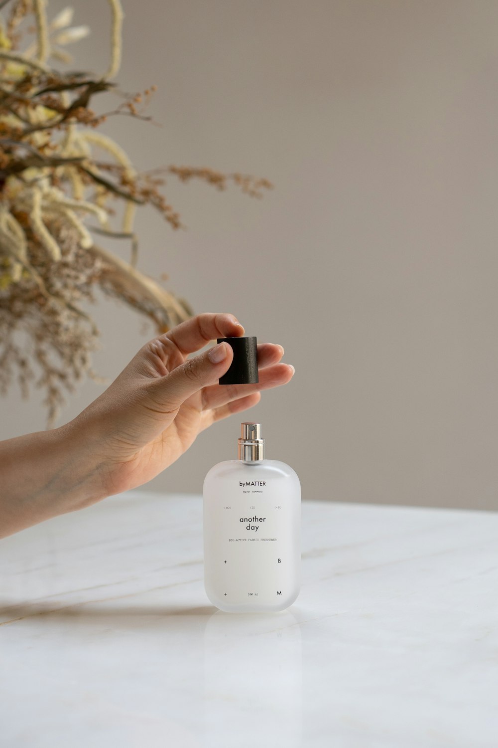 a person holding a bottle of perfume on a table