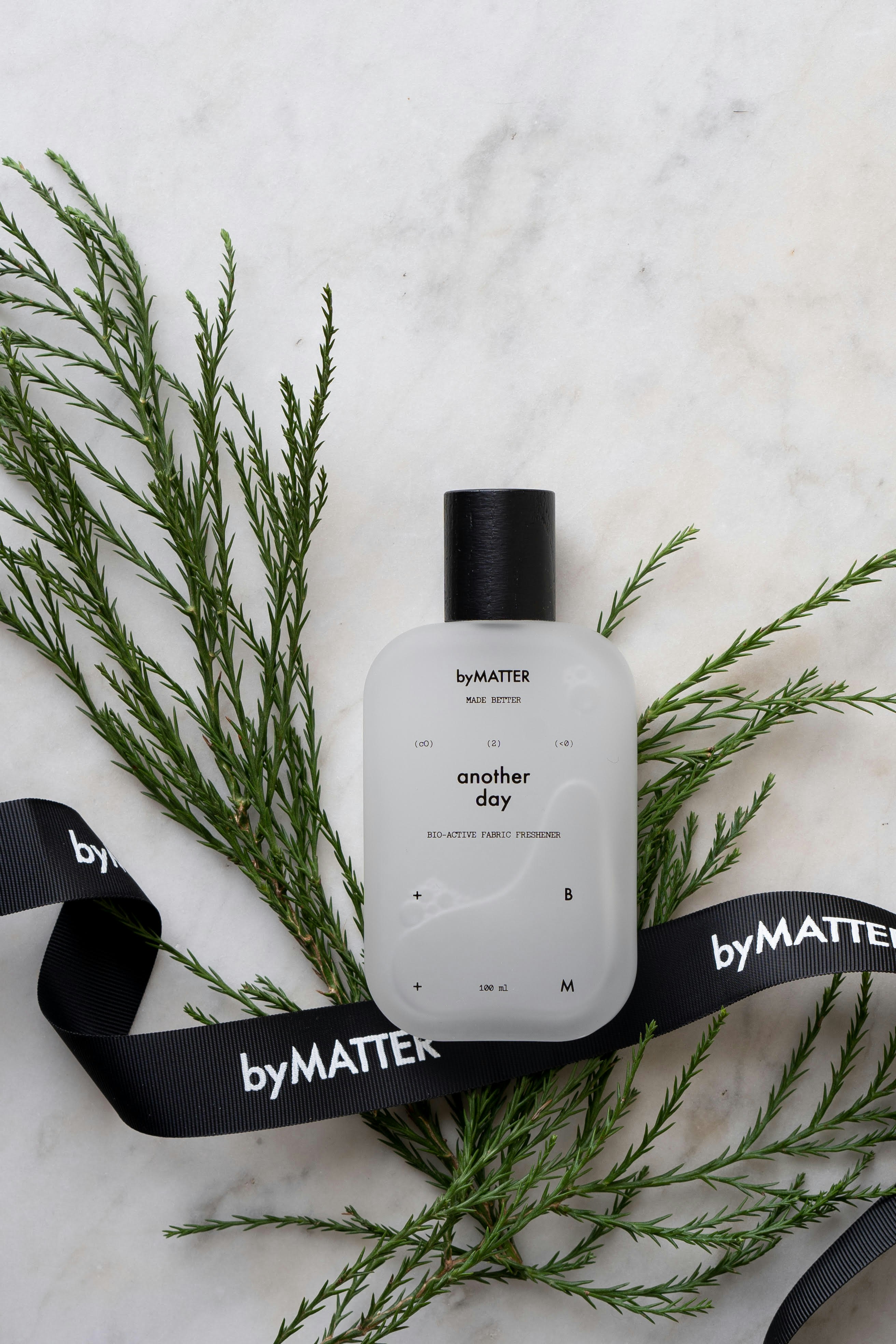 Clear botanical spirit bottle with white floral elements on marble surface