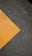 A textured asphalt surface with a prominent diagonal yellow paint stripe running across it. The paint appears slightly worn, contrasting against the dark, rough texture of the asphalt.