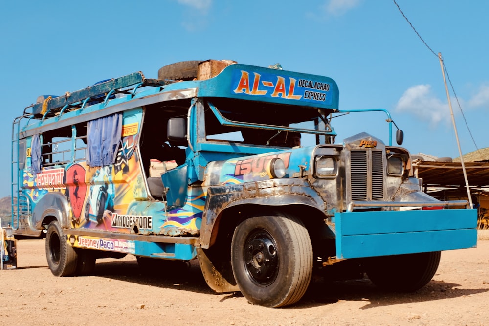 a blue bus parked on top of a dirt field