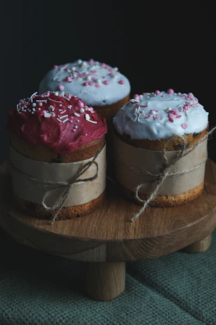 Close-up of colorful cupcakes arranged on a rustic wooden table with soft natural light.
