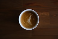 A steaming mug of freshly brewed coffee with crema swirling on top, set on a rustic table.