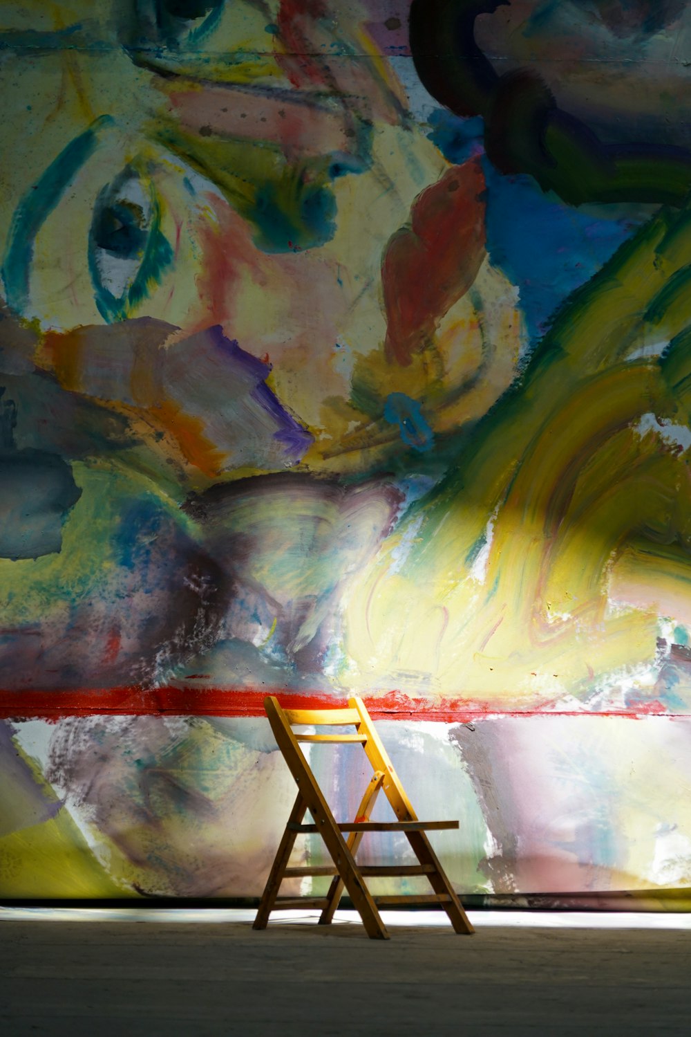 a wooden chair sitting in front of a painting