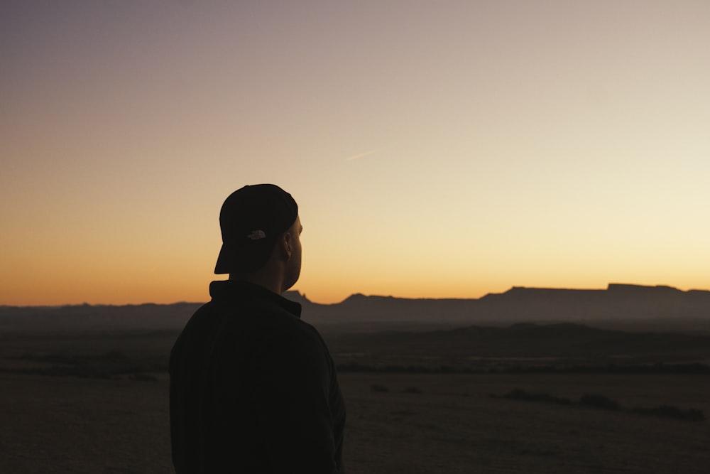 a man standing in the middle of a desert at sunset