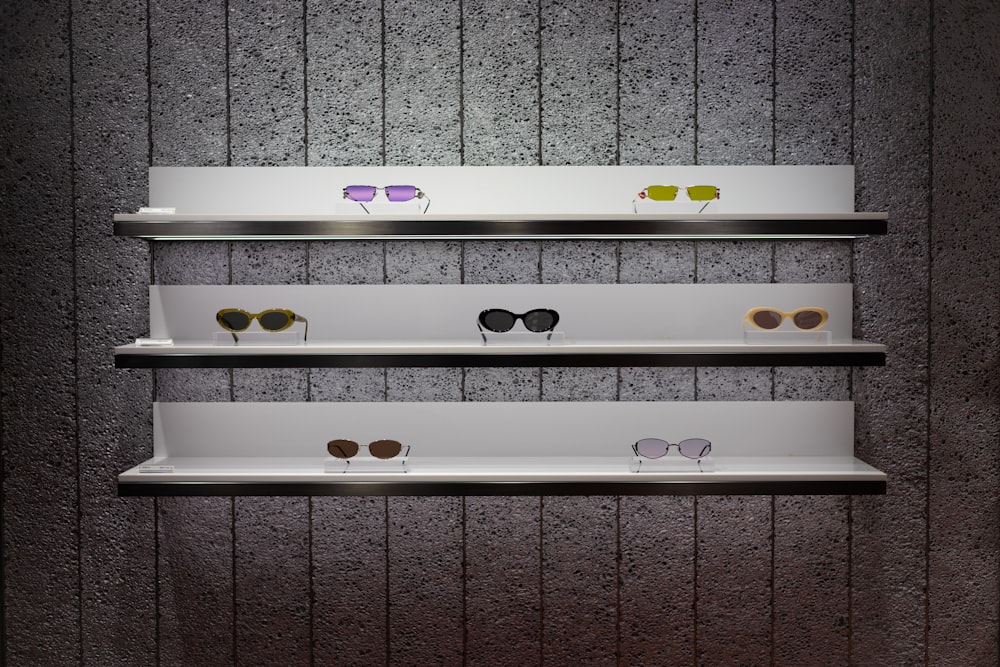 three white shelves with sunglasses on them