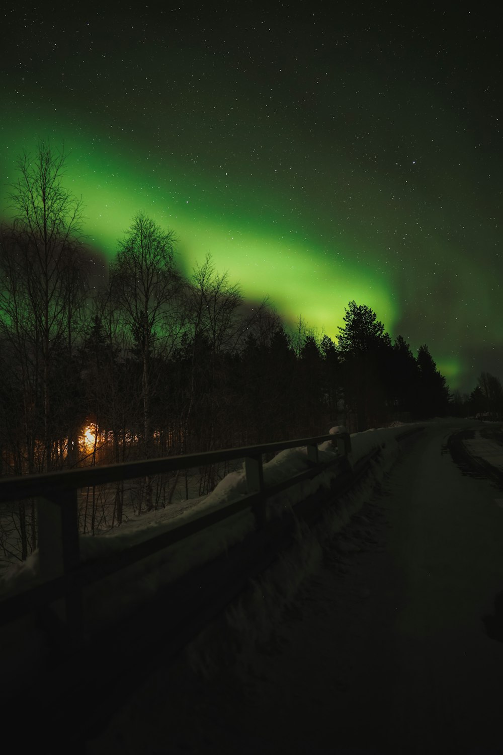 Una aurora verde y negra sobre una carretera nevada