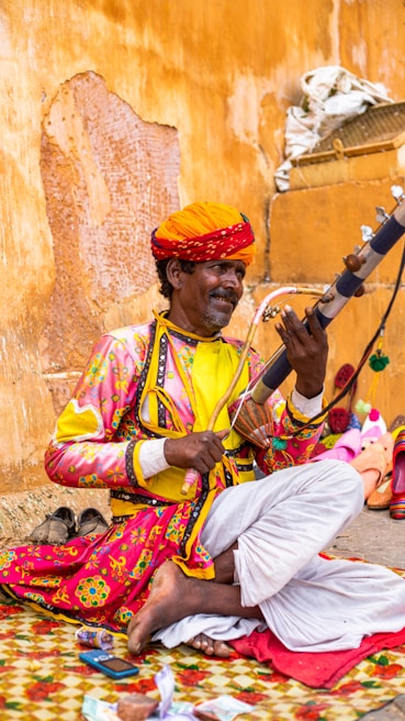 a man sitting on the ground playing a musical instrument