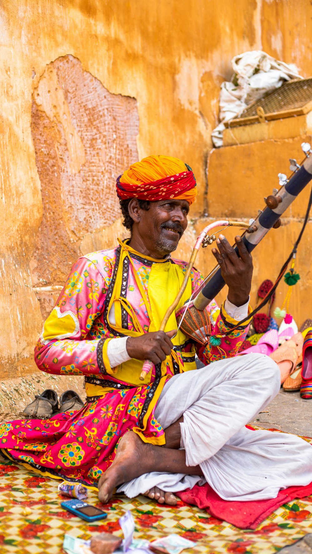 a man sitting on the ground playing a musical instrument