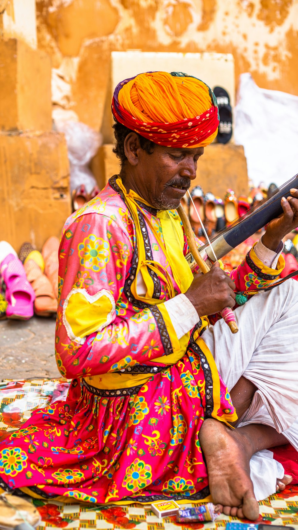 a man sitting on the ground playing a musical instrument