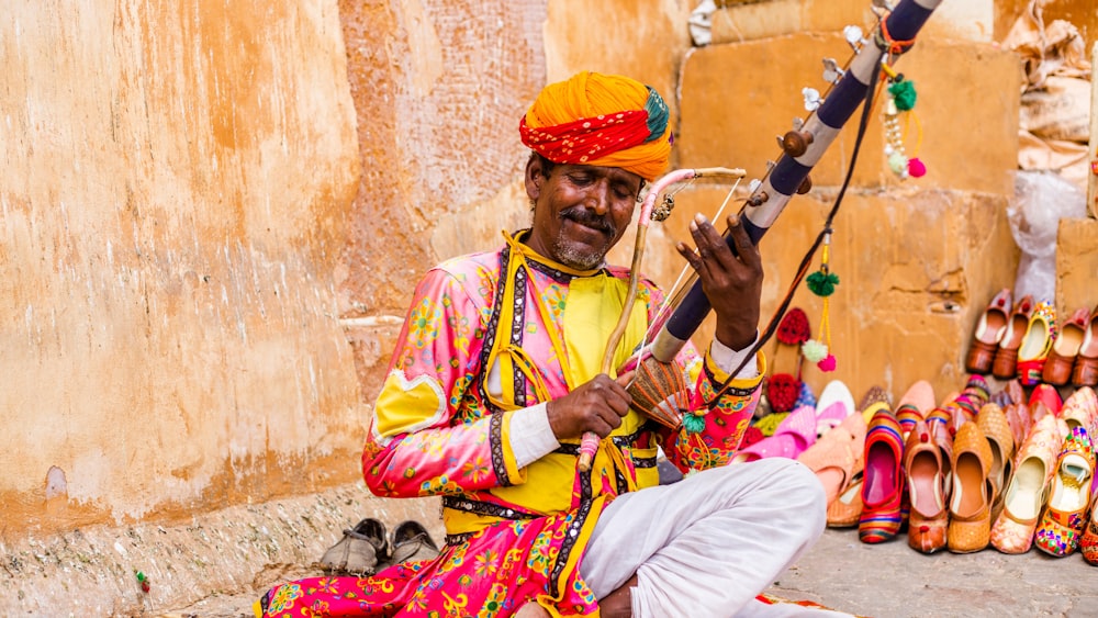 a man sitting on the ground playing a musical instrument